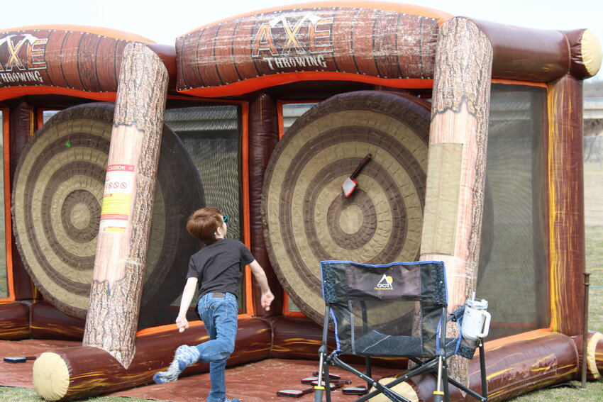 A student throws a plastic axe at the axe-throwing bounce house.