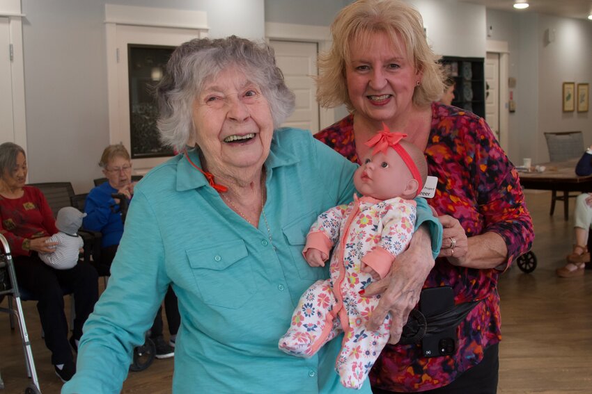 Legacy Oaks of Azle memory care resident Shirley holds her baby doll and smiles next to Mary Greer March 6.