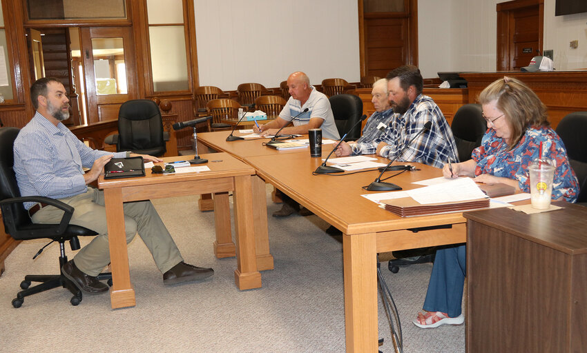 Adam Endicott with Agri-City Insurance (left) was at Tuesday's meeting of the Commissioners to present a premium refund on the county's health insurance.