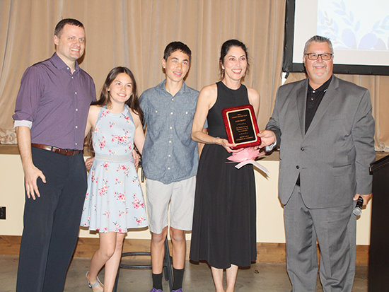 Sandy Brown receives the Citizen of the Year Award from last year's recipient, Ken Kwapnioski. Also pictured are members of Sandy's family, Matt Ley, Josie Ley and Mason Ley.