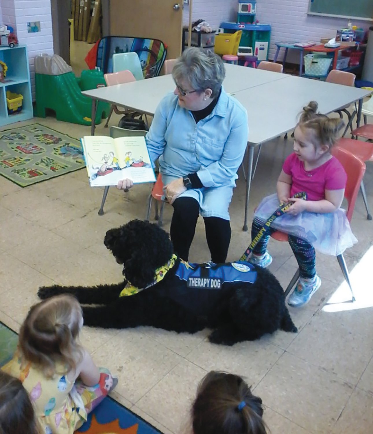 Louie, a therapy dog, and Nan Rix read to students during a recent school visit