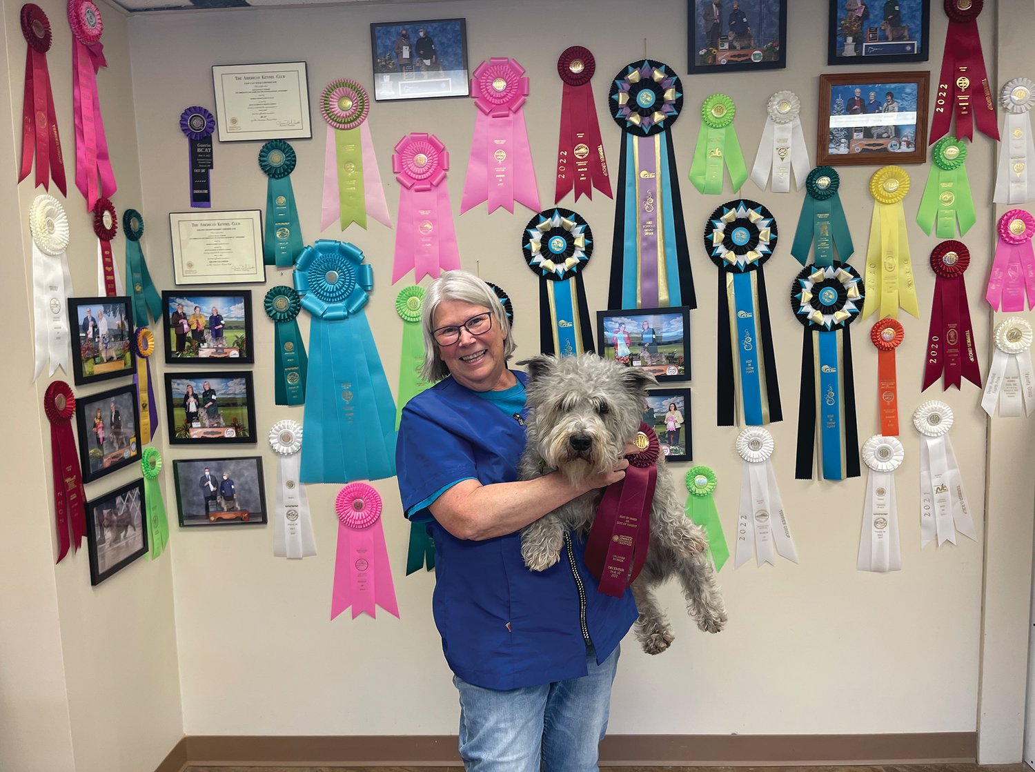 Dawn Jacobson and her dog Guerin pose beside some of the awards they have received in recent years.